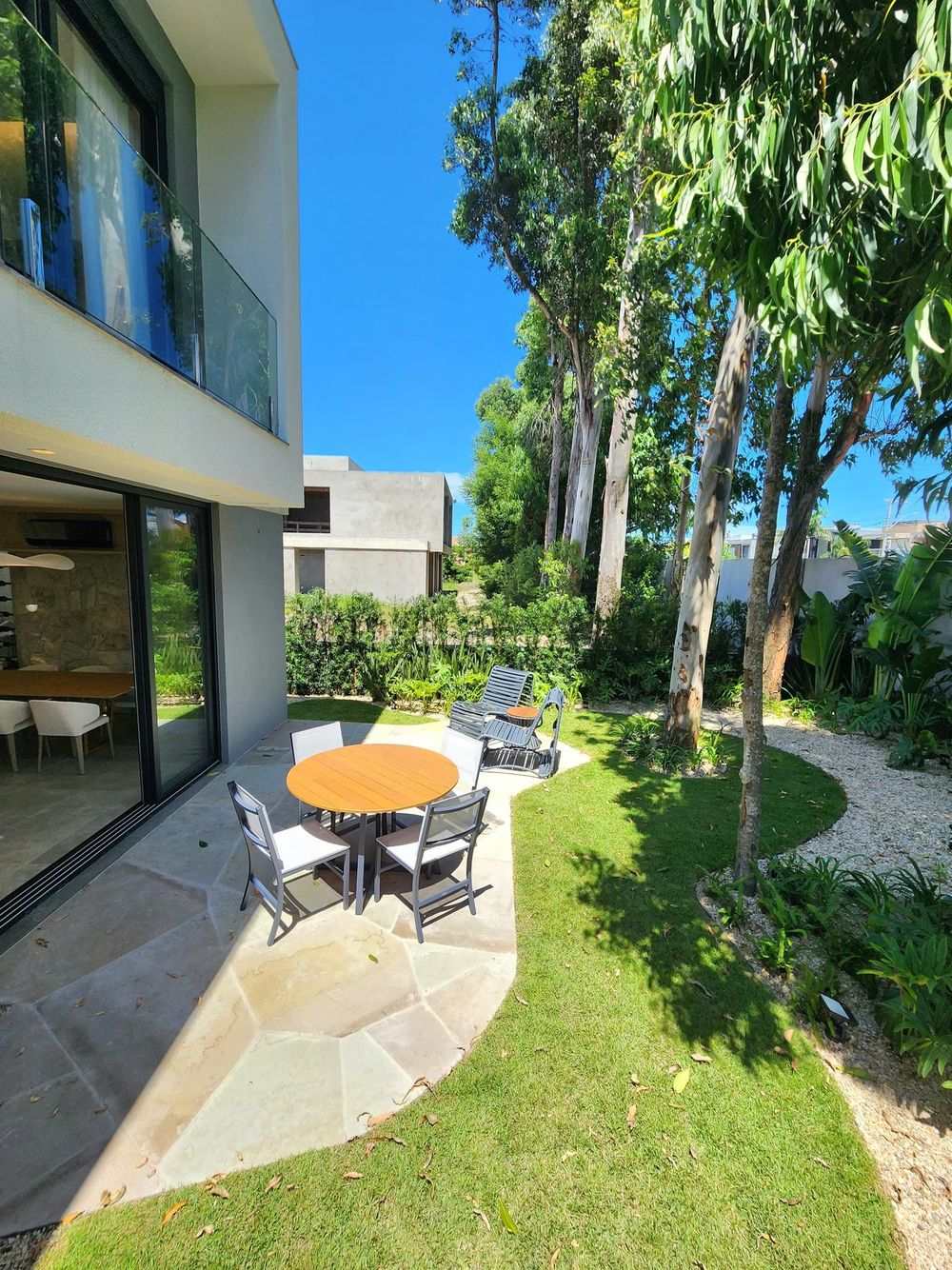 Jardim lateral da casa, com mesa externa sob as árvores