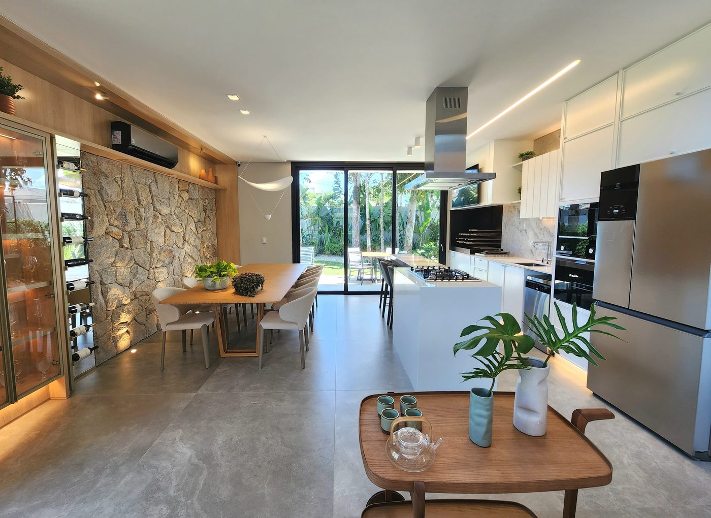 Living integrado à cozinha, com parede de pedra e vista para o jardim