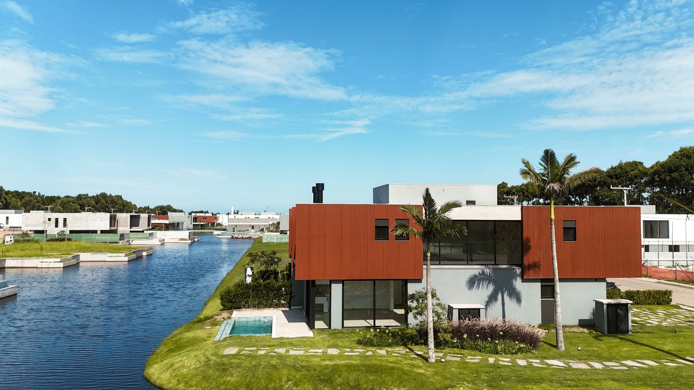 Casas alinhadas na margem do canal, com piscinas privativas