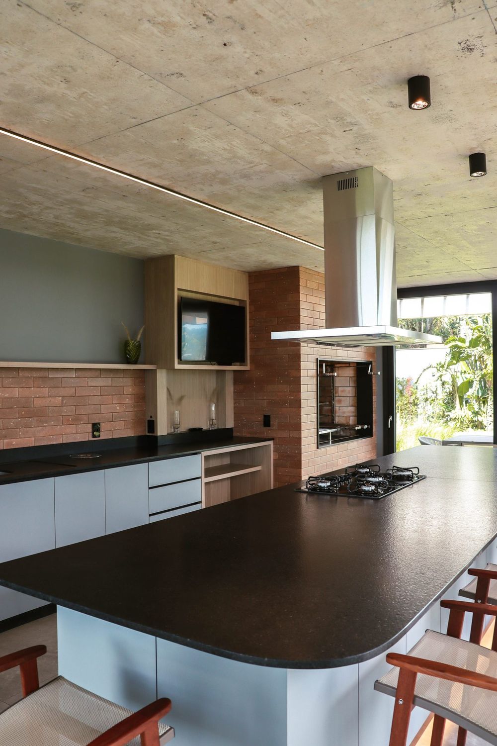 Cozinha do espaço gourmet, com bancada de pedra e churrasqueira embutida