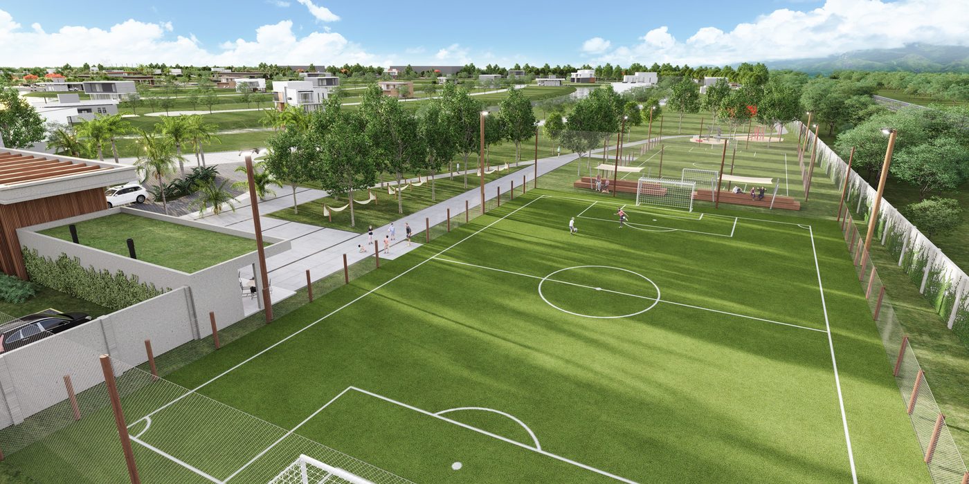 Campo de futebol gramado, cercado, com os lotes ao fundo