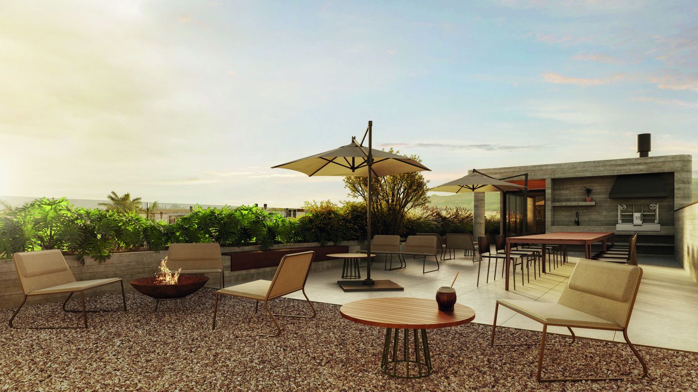Lounge do rooftop com guarda-sol e poltronas