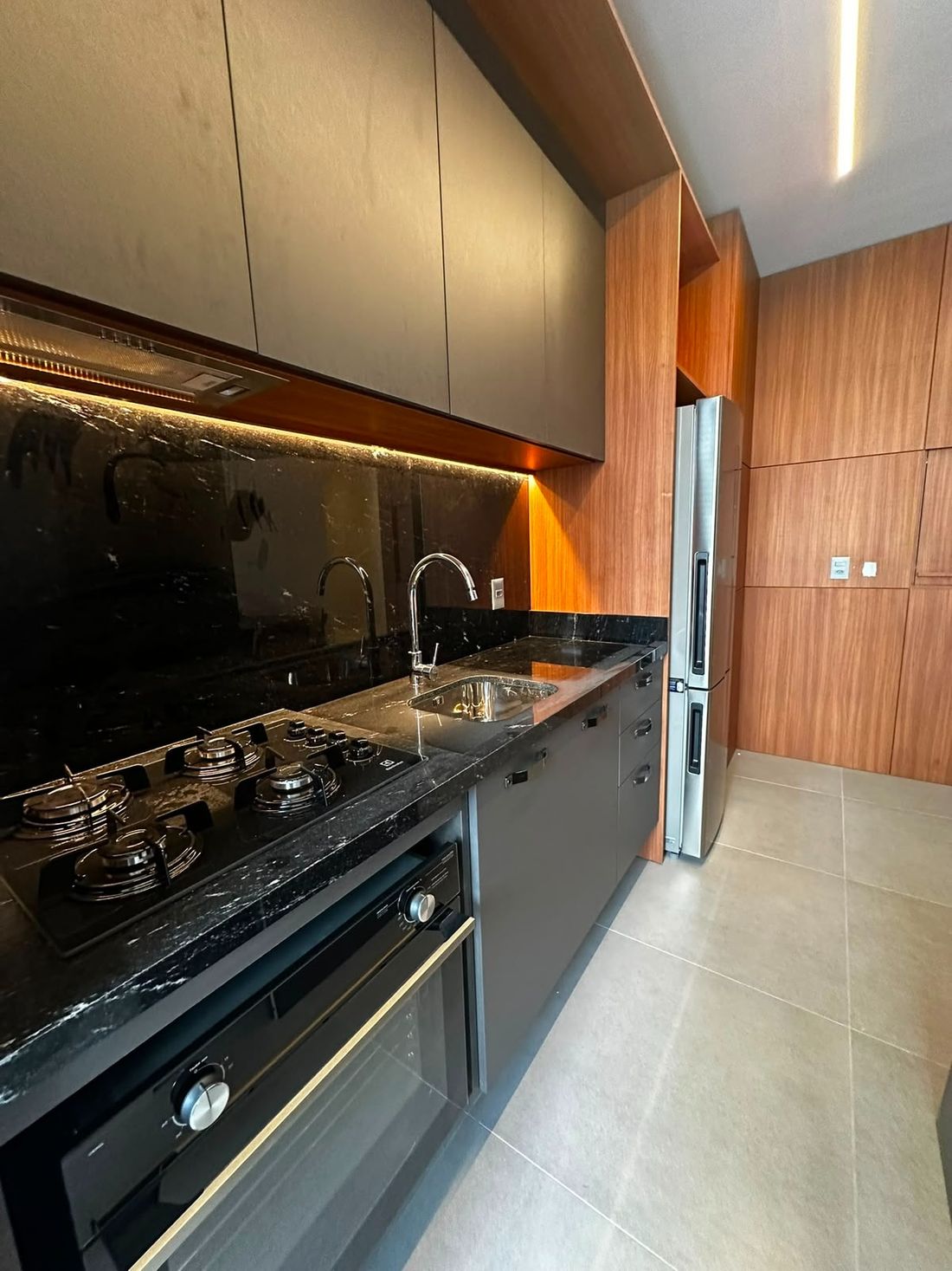 Cozinha com bancada em pedra escura e armários planejados