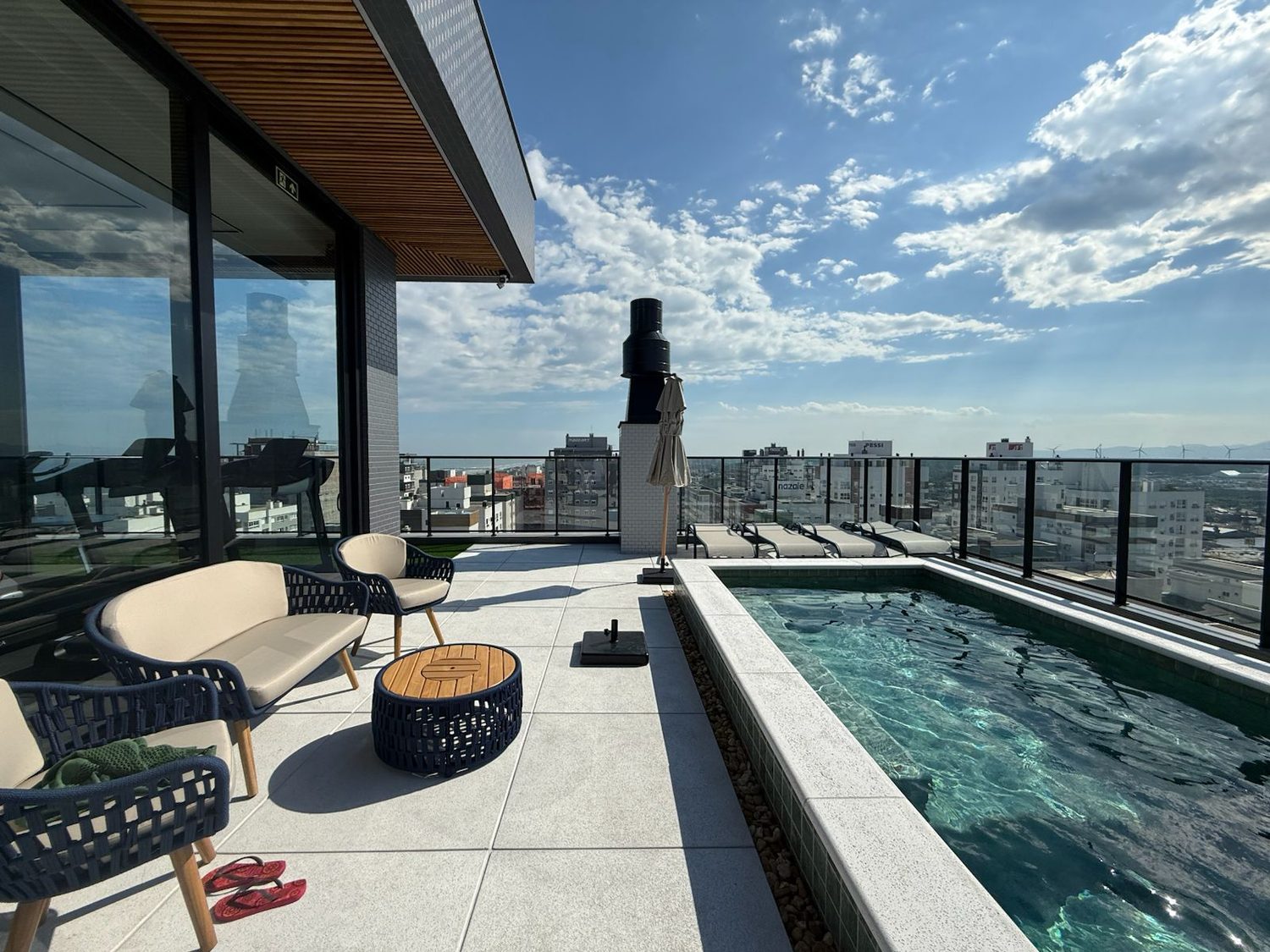 Deck do rooftop com espreguiçadeiras ao lado da piscina
